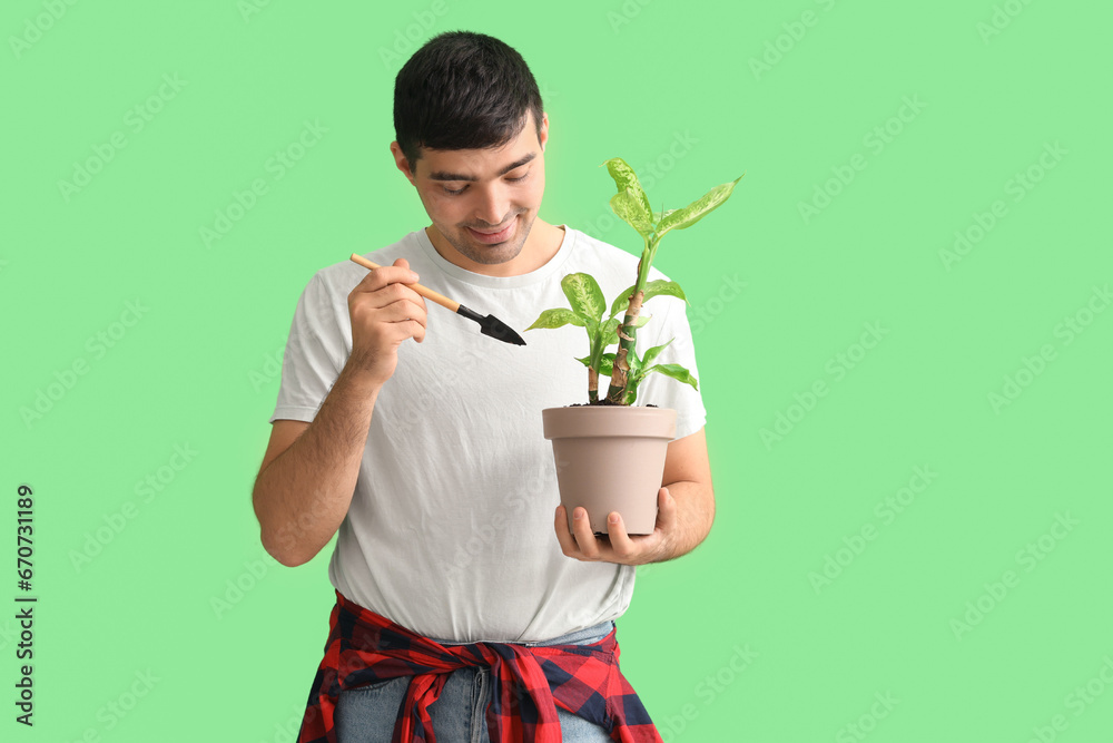 Young man with shovel and plant on green background Young man with shovel and plant on green background