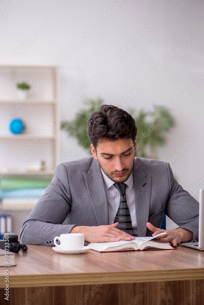 Young male employee reading book in the office Young male employee reading book in the office
