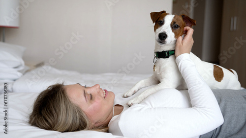 Dog friendly hotel. A girl and a dog sleep in a white bed at home. Happy mixed breed dog in a luxury bed. Pets are allowed at the hotel. Dog on the bed in a hotel room.