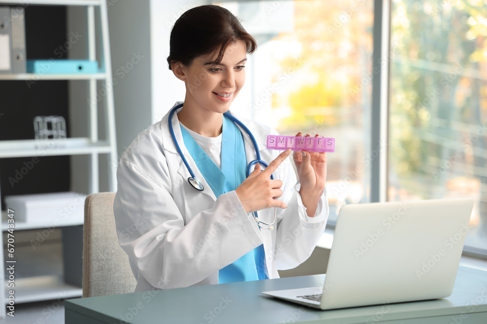 Female doctor with pill box video chatting in office Female doctor with pill box video chatting in office