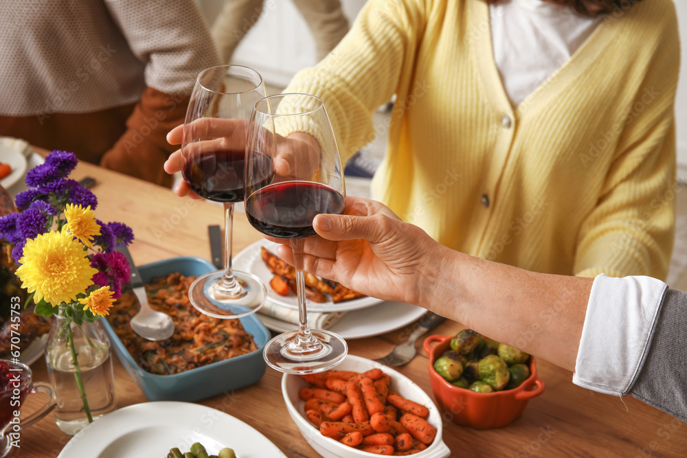 Young woman with her mother having dinner at festive table on Thanksgiving Day, closeup