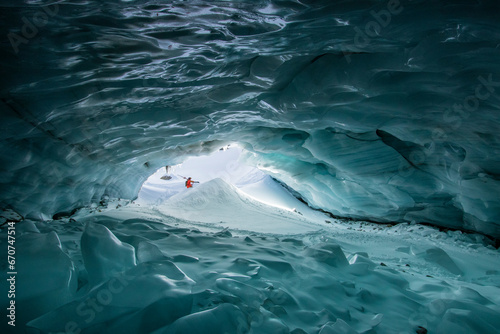 Skier with ski poles exploring cave on snow mountain photo