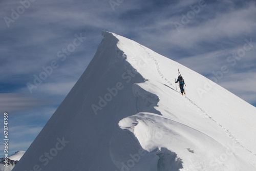 Unrecognizable person climbing snowcapped mountain peak