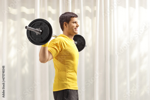 Man standing and lifting weights on shoulders at home