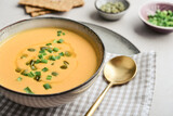 Pumpkin soup in a bowl with pumpkin seeds, green onions and breadsticks