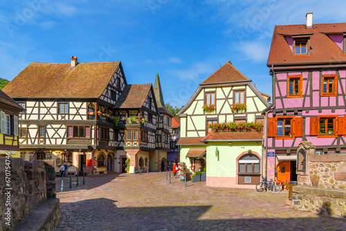 A small cobblestone square near the Castle Bridge with colorful half timber buildings with shops and cafes in the Alsatian village of Kaysersberg, France.