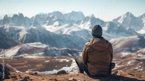 Young one sits and gazes at the snowy mountains