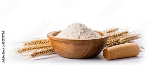 A wooden bowl on a white background containing wheat and flour are separated from other objects