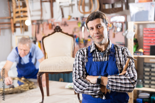 Confident male carpenter showing around local furniture workshop
