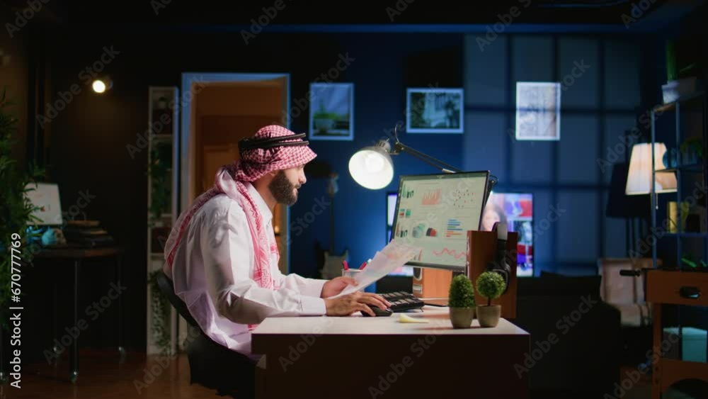 Muslim teleworker crosschecking analytics statistical data set with paperwork while remotely working in dimly lit apartment office. Hardworking Arab employee optimizing key performance indicators Muslim teleworker crosschecking analytics statistical data set with paperwork while remotely working in dimly lit apartment office. Hardworking Arab employee optimizing key performance indicators