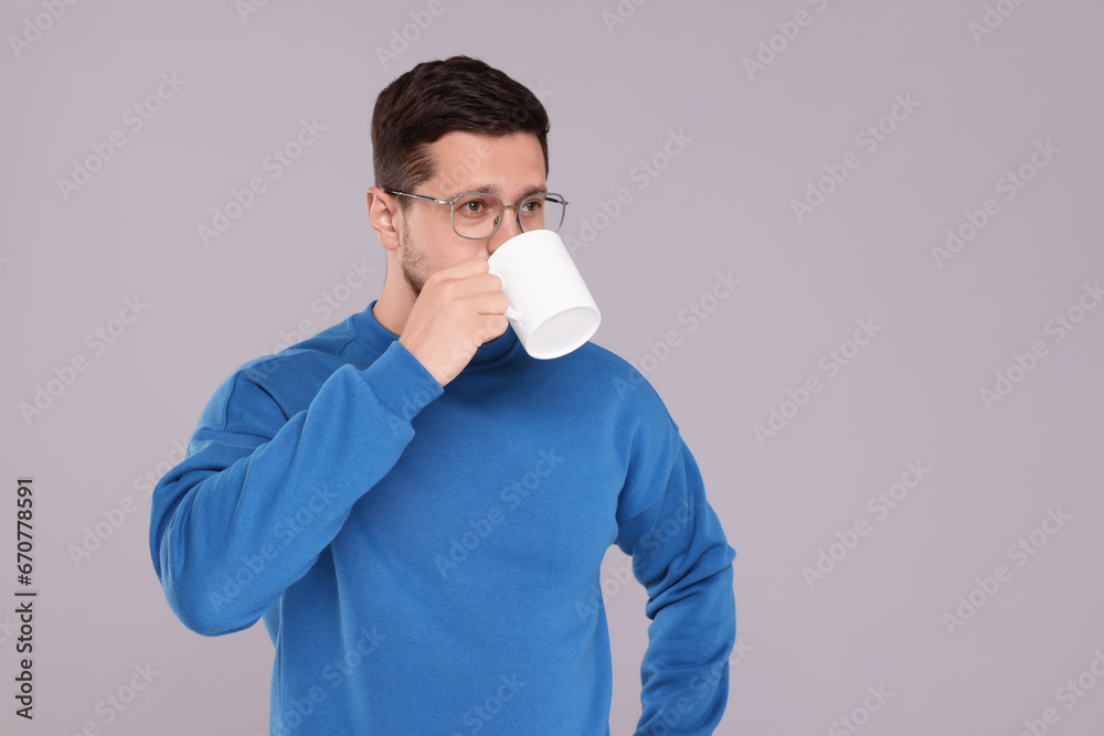 Man drinking from white mug on grey background. Space for text Man drinking from white mug on grey background. Space for text