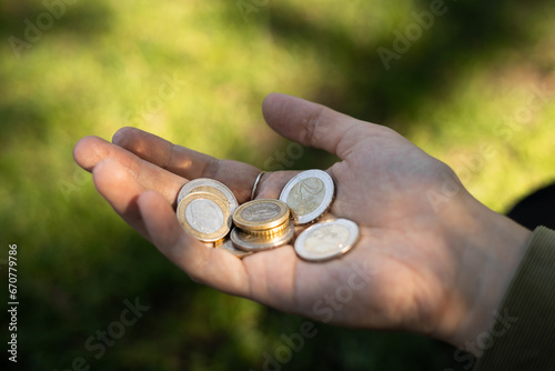 Woman hand with euro coins with green grass with sun on background