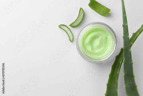 Jar of natural cream and cut aloe leaves on white background, flat lay. Space for text