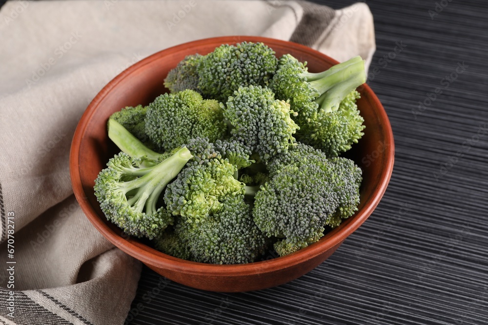 Bowl with fresh raw broccoli on black wooden table Bowl with fresh raw broccoli on black wooden table