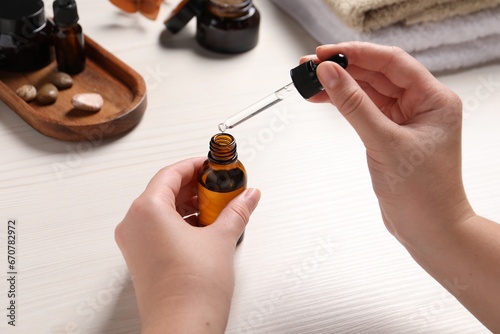 Woman with bottle of cosmetic serum and pipette at white wooden table, closeup