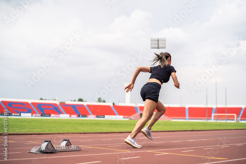 Asian young sportswoman sprint on a running track outdoors on stadium. 