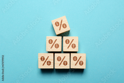 Wooden cubes with percent signs on light blue background  top view
