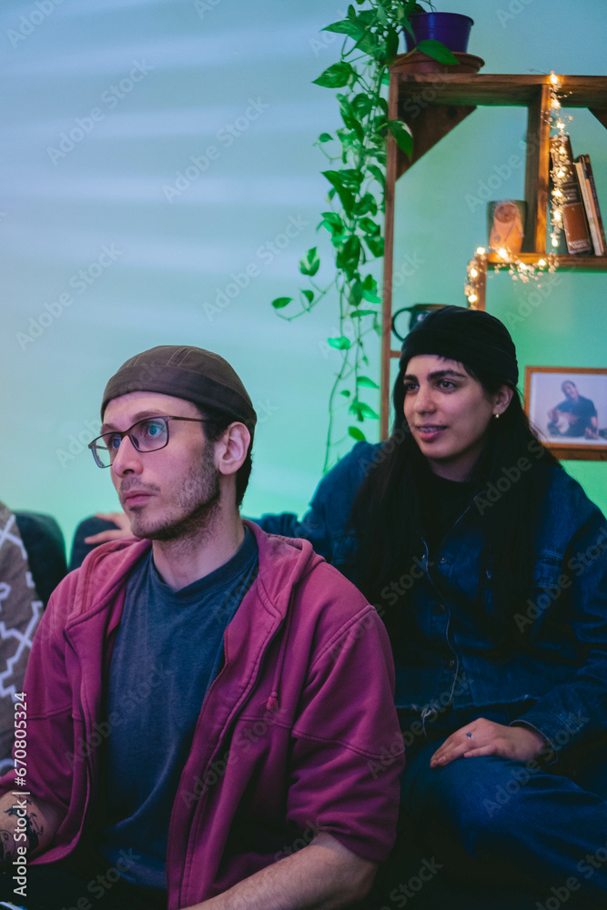 Fototapeta premium two latin friends a young woman and a young man watching tv in a student apartment
