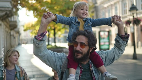 Happy little girl having fun on her fathers shoulder in the city
