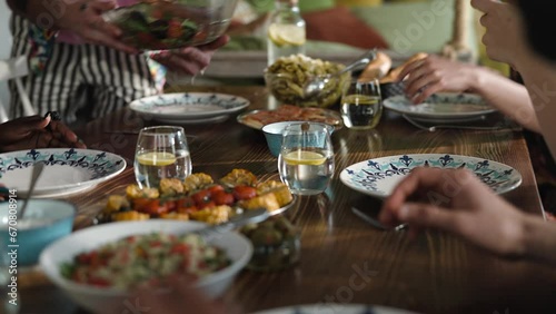 Young man presenting food to his friends at the table in a rented apartment