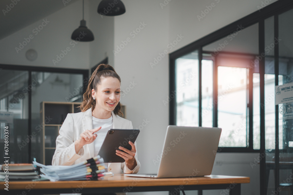 Female business woman using tablet and laptop for analyzing the business report in the office Female business woman using tablet and laptop for analyzing the business report in the office