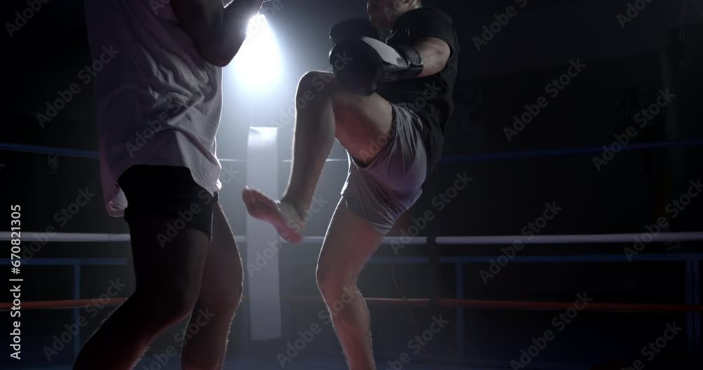 Muay Thai fighter striking opponent with a leg kick inside boxing ring ...