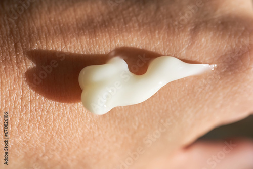 A smear of white moisturizer or sunscreen on a woman's hand.