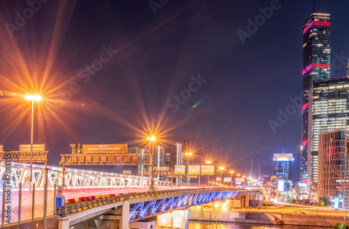 The scyscrapers of the Moscow City at night and the Dorogomilovsky bridge with illumination. Translation of text - street names: Krasnopresnenskaya, center, etc.