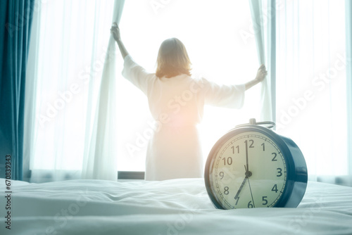 Morning of a new day, alarm clock wake up woman sitting in the room. A woman stretch the muscles at window. Health and care concepts photo