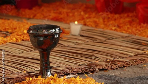 day of dead celebration, altar decorated with colorful yellow cempazuchitl yellow flower, candle, traditional handmade mexican carpet called petate, burning incense in a traditional copal made of clay photo