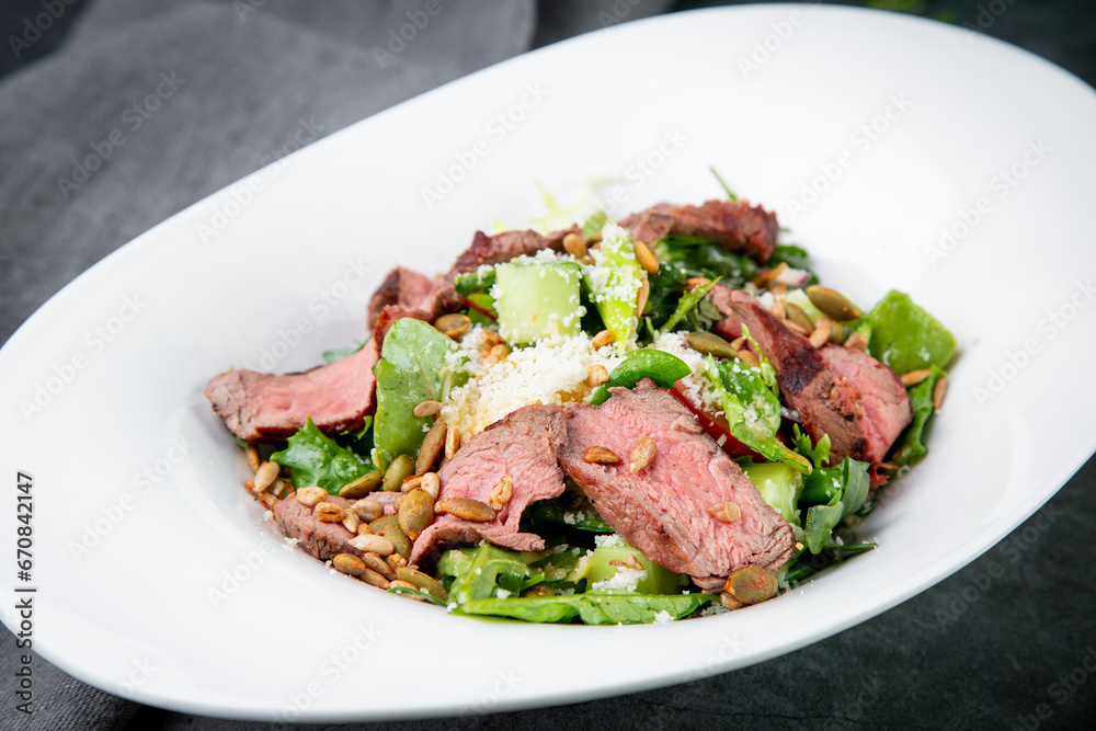 salad with pieces of beef, pistachios, lettuce and cheese side view