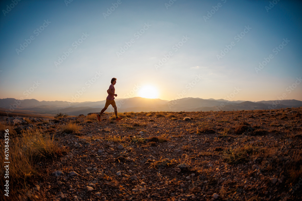 Running in the mountains..running athlete on the background of mountain peaks. Skyrunning. A person trains outdoors, leads an active lifestyle.