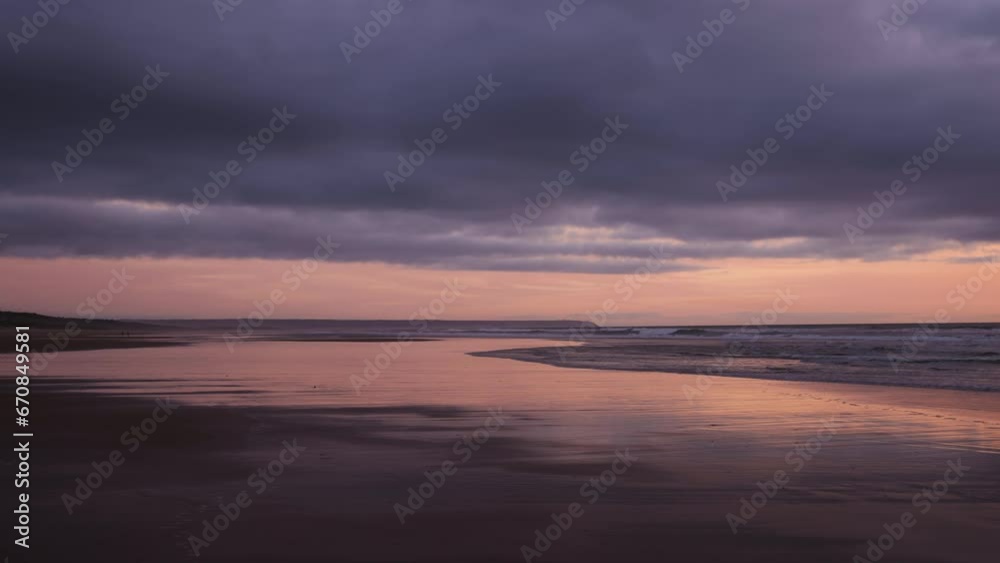 Colorful sunset on the beach timelapse. Low tide reflections as waves lap the shore Colorful sunset on the beach timelapse. Low tide reflections as waves lap the shore