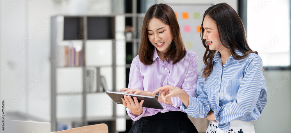 Two smiling businesswoman working together on digital tablet. Creative female executives meeting in an office using digital tablet. Two smiling businesswoman working together on digital tablet. Creative female executives meeting in an office using digital tablet.