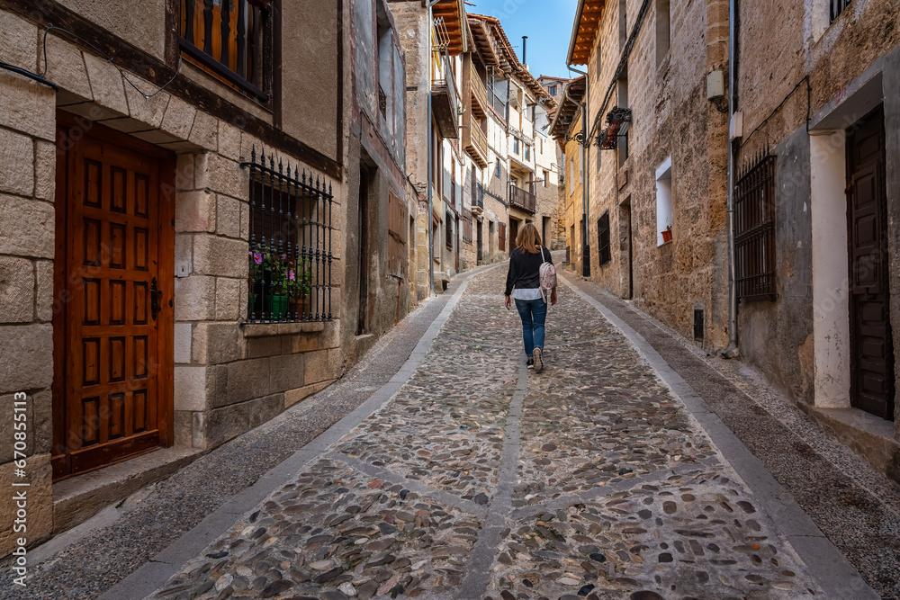 Tourist woman strolling down an alley with cobblestone floor in the medieval town of Frias, Burgos.