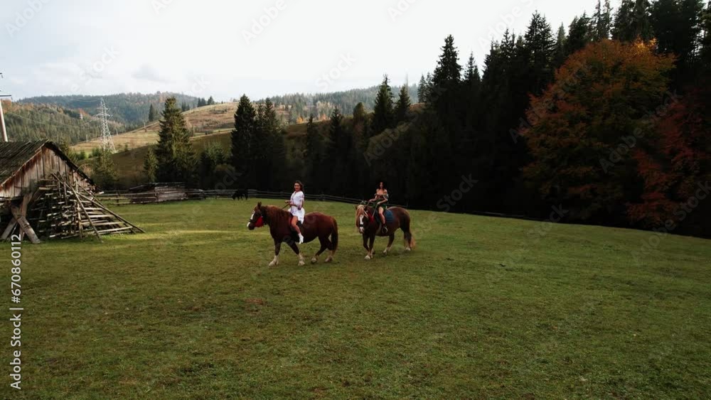 Cute young women ride horses in national Ukrainian dresses in the Carpathian mountains.Drone shot 4k Cute young women ride horses in national Ukrainian dresses in the Carpathian mountains.Drone shot 4k