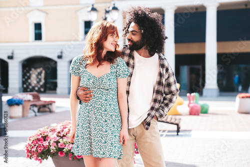 Smiling beautiful redhead woman and her handsome boyfriend. Model in casual summer clothes. Happy cheerful family. Female having fun. Couple posing in the street at sunny day
