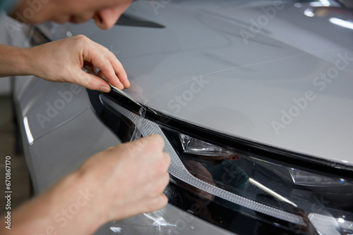 Worker detailer cutting off excess of polymer protective outer coating closeup