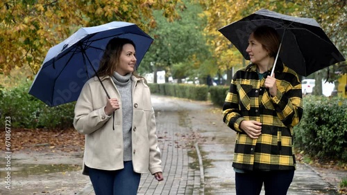 mother-in-law and daughter-in-law walking together with umbrella in autumn park, Wroclaw, Poland