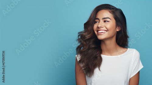 Hispanic woman standing in front of a blue background, showing a cheerful and caring smile. Romantic concept.