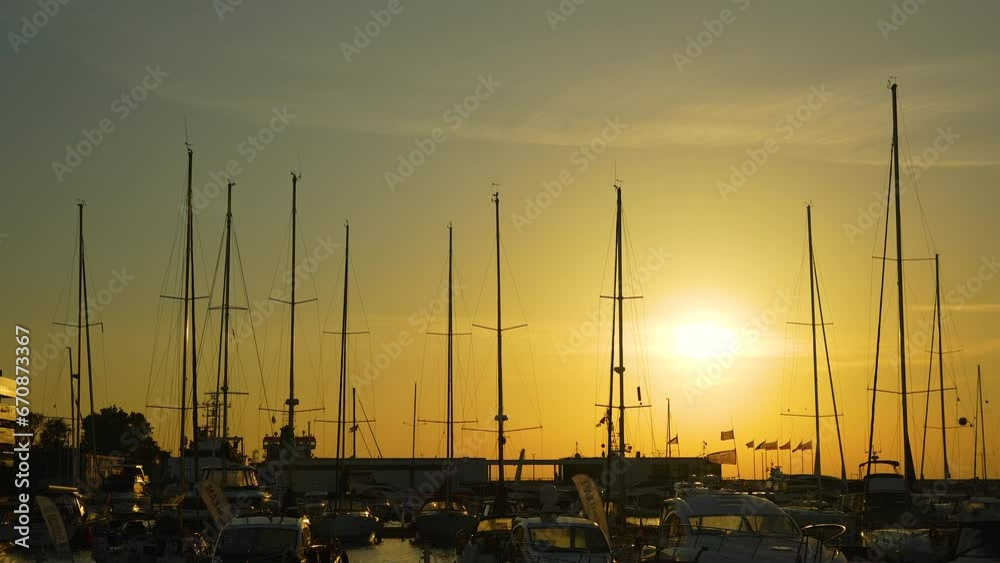 Golden sunset illuminates a marina filled with moored sailboats, casting long shadows and a serene glow Golden sunset illuminates a marina filled with moored sailboats, casting long shadows and a serene glow