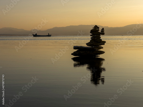 Photography fishing boat on the lake, zen stones and serenity, simplicity and peace at sunse