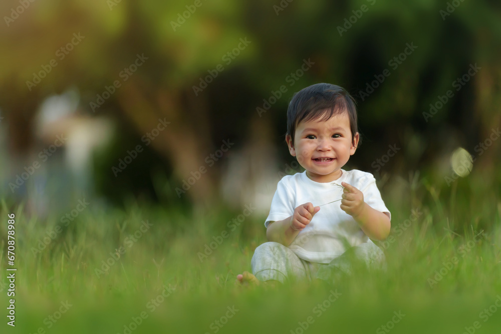 happy infant baby sitting on green grass field at the park happy infant baby sitting on green grass field at the park