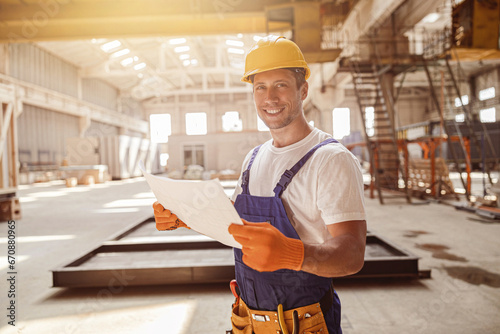 Cheerful male worker holding building architectural plan