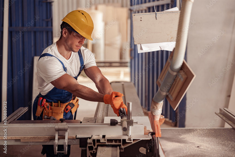 Serious male worker using woodworking machine in workshop Serious male worker using woodworking machine in workshop