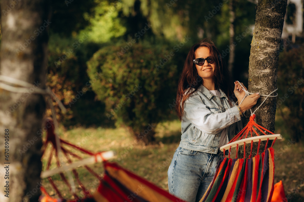 Obraz premium A woman ties a hammock to a tree
