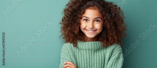 Cute kid girl in green sweater planning with hands together looking askance photo
