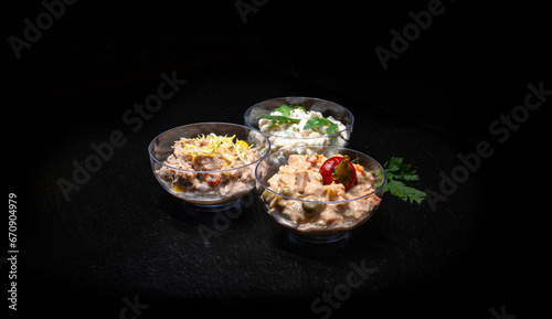 Different types of salads in a glass bowl on a black background.