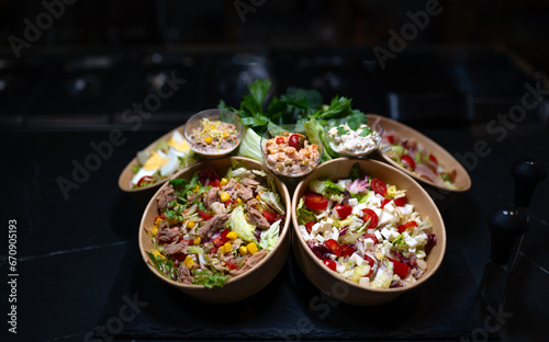 Different types of salads in a bowl on black background.