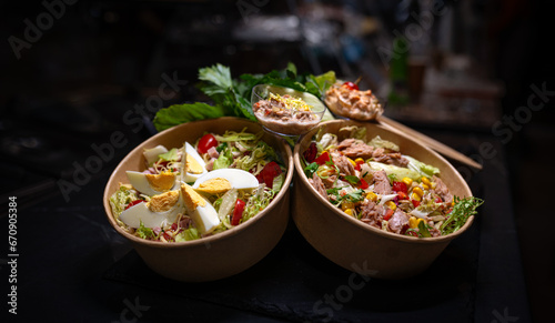 Different types of salads in a bowl on black background.